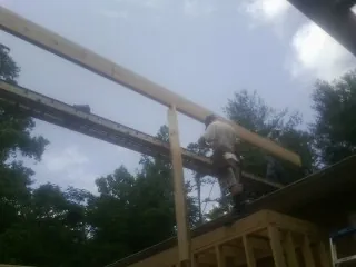 Carpenter setting a ridge beam over a new addition frame — Ice Dam Removal by Roofing Brothers in Freeville