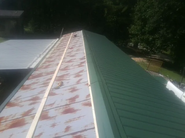 Old rusted panels beside newly installed green metal roofing — Wind Damage Roof Repair by Roofing Brothers in Freeville