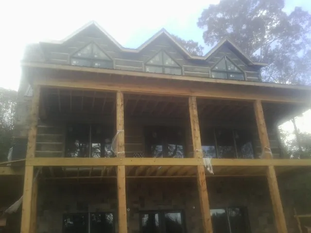 Dormers and porch framing on a large log home under construction — Roof Coating work by our crew in Freeville