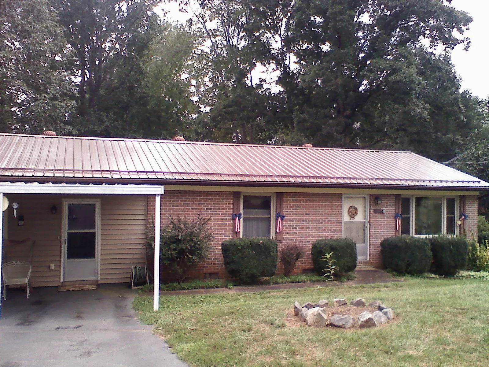 Bronze metal roof and carport on a brick ranch home — Roof Repair work by our crew in Freeville