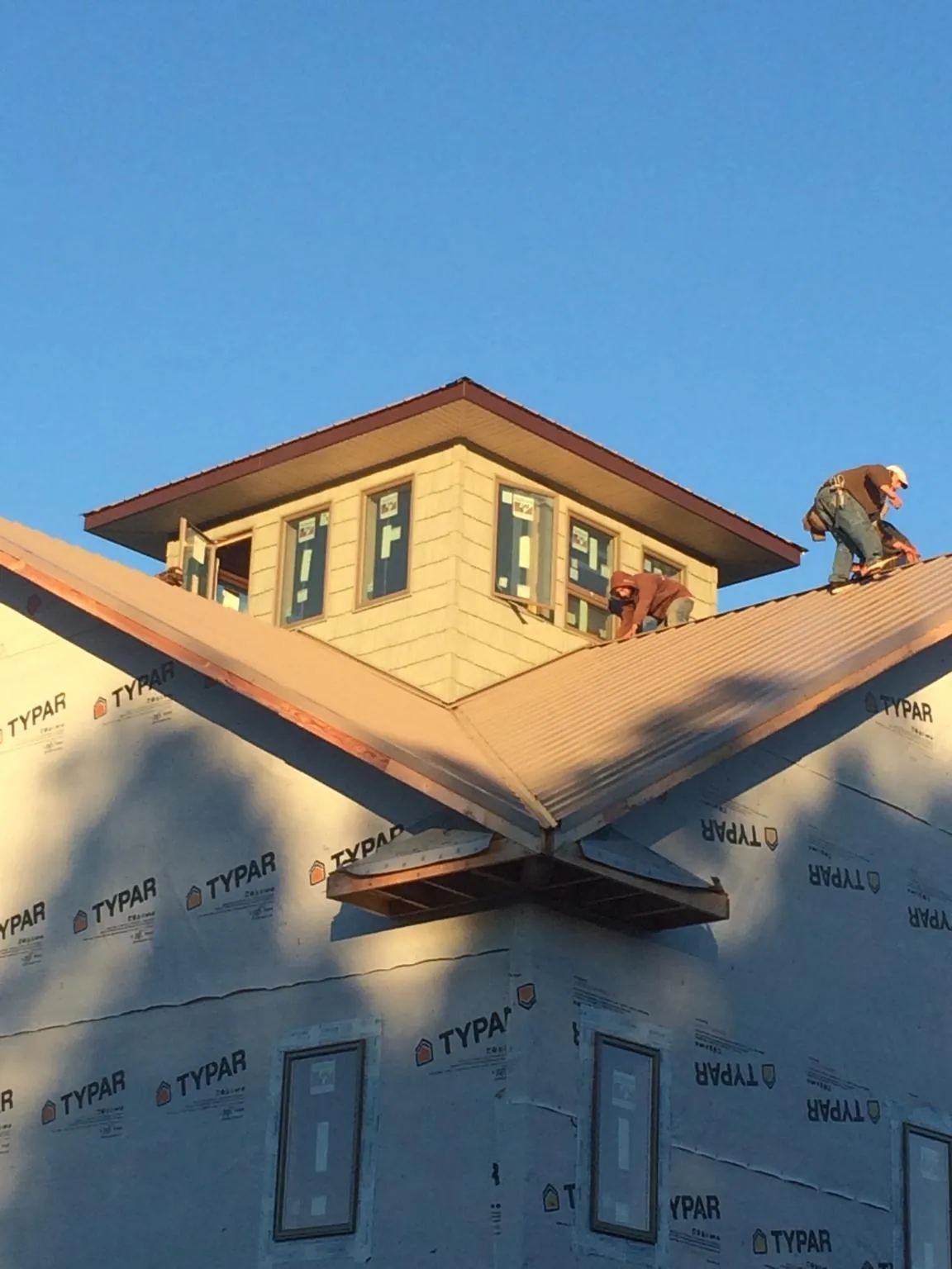 Roofers working around a rooftop cupola on a new metal roof at sunset — Roof Waterproofing in Freeville by Roofing Brothers